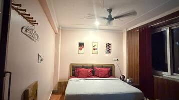 A bedroom with a bed, a ceiling fan, a window, and a nightstand.
