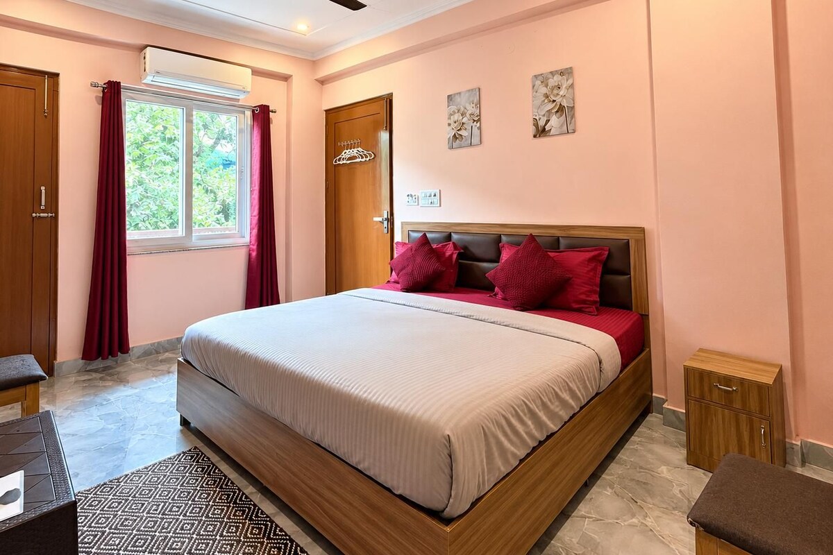 A bedroom with a bed, a ceiling fan, a window with curtains, and a door.