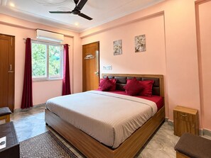 A bedroom with a bed, a ceiling fan, a window with curtains, and a door.