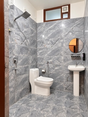 A bathroom with a shower, toilet, and sink, all against a marble wall. - Stay Berry (Rishikesh)