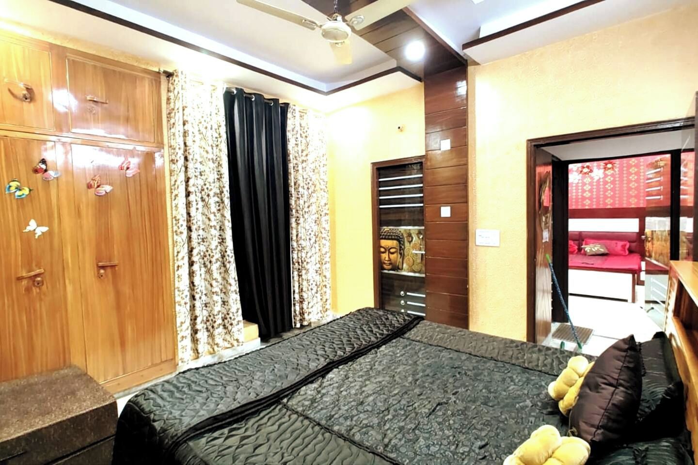 Un dormitorio con cama, armario, cortinas y una estatua de Buda.