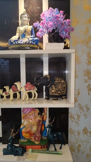 Una estantería con una estatua de Buda, una planta en maceta y varias figuritas, entre ellas camellos y un elefante.