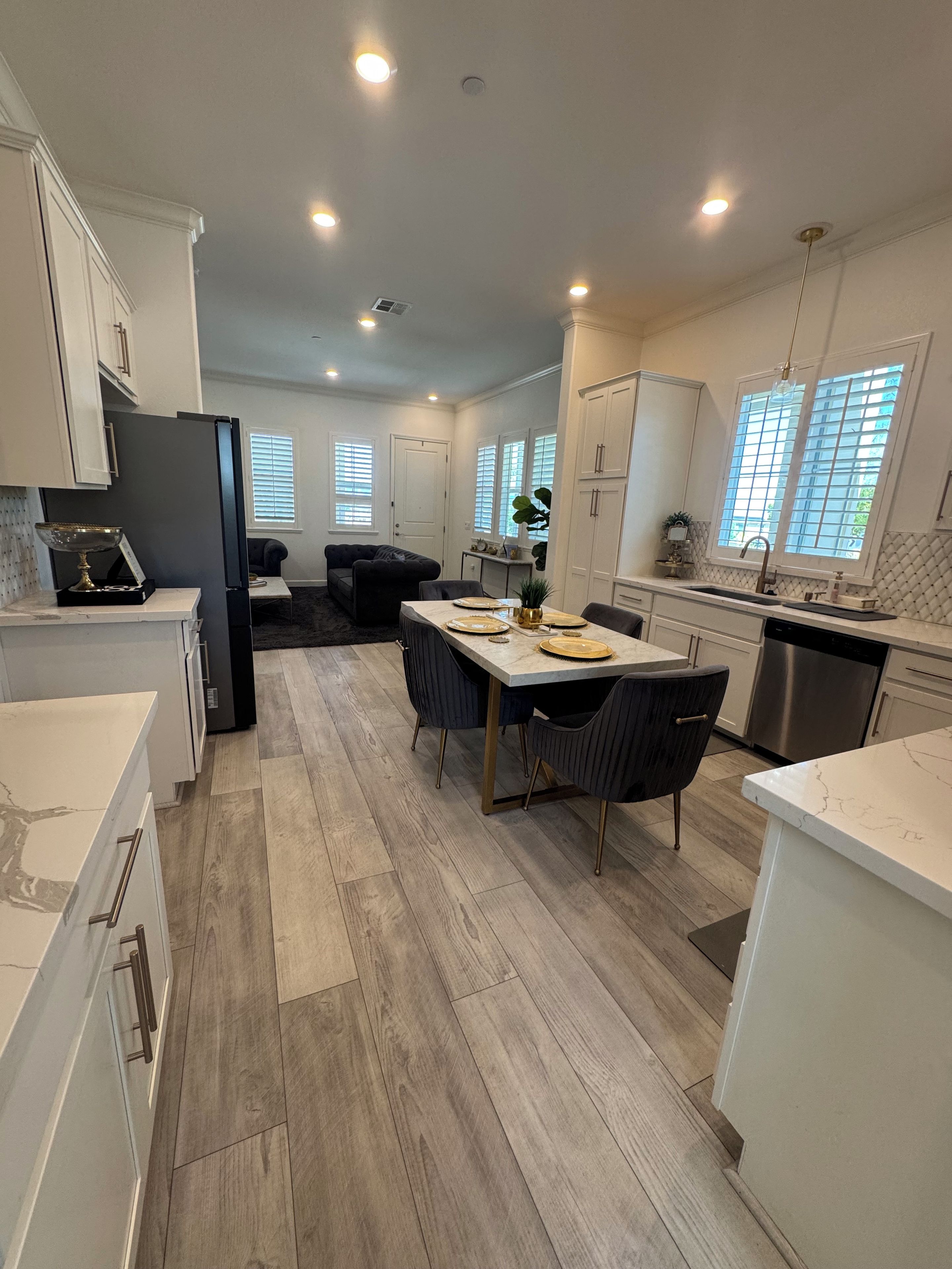 A modern kitchen with white cabinetry, a dining area with a table set for four, and a built-in oven.