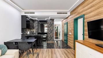 A modern kitchen with a black marble backsplash, a dining area with a black table and chairs, and a wooden accent wall with a TV.