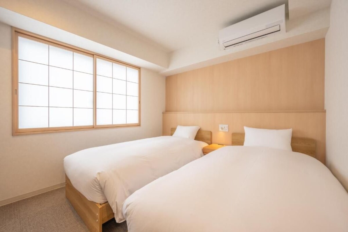 Et hotelværelse med to senge, et stort vindue og en aircondition.