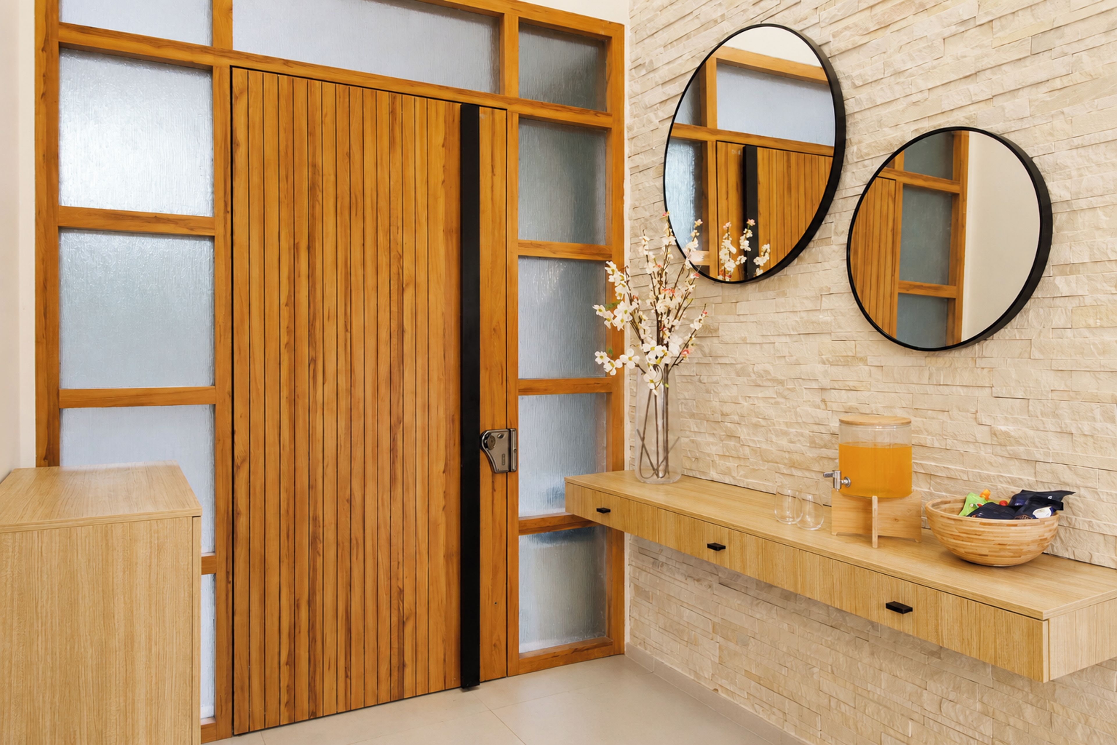 Een houten garderobe met gefroste glazen panelen, een houten kaptafel met spiegel en een muur met een steenachtige textuur.