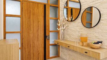Een houten garderobe met gefroste glazen panelen, een houten kaptafel met spiegel en een muur met een steenachtige textuur.