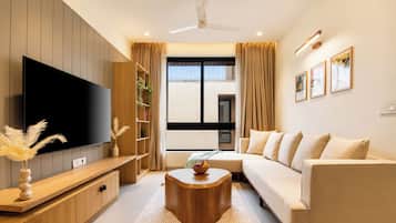 A modern living room with a flat-screen TV, a wooden coffee table, a sofa, and a bookshelf.