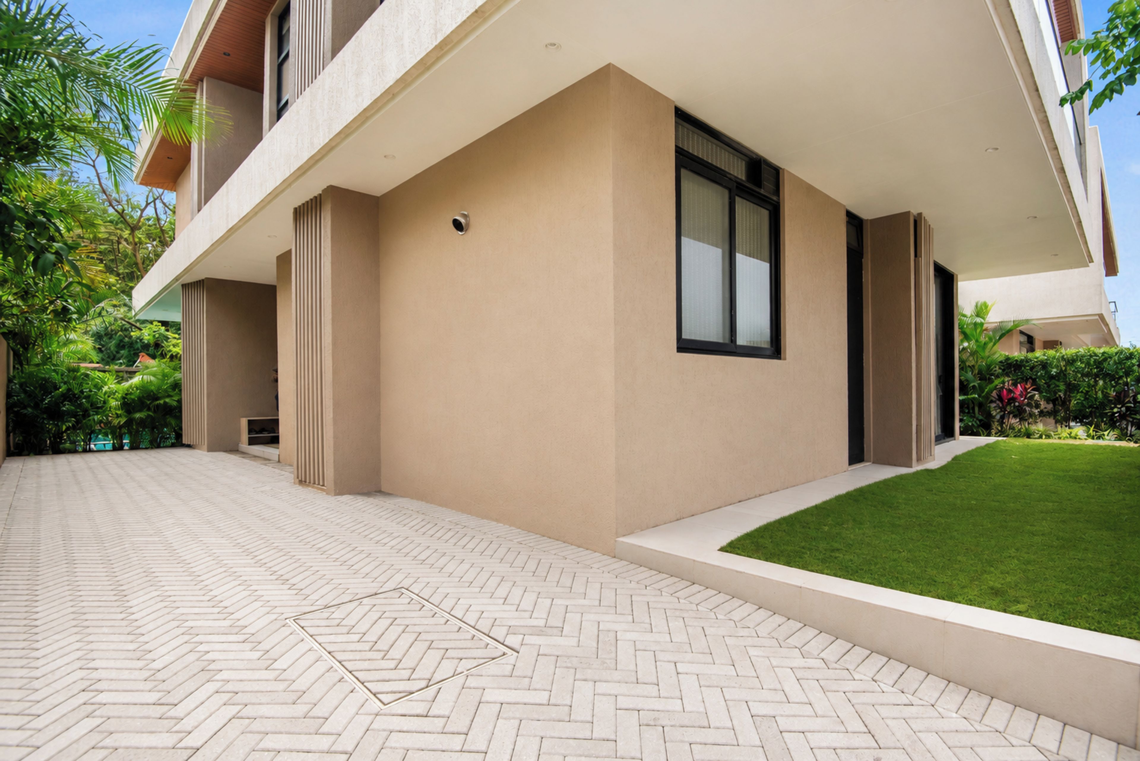 A modern building with a flat roof, large windows, and a paved entrance area.