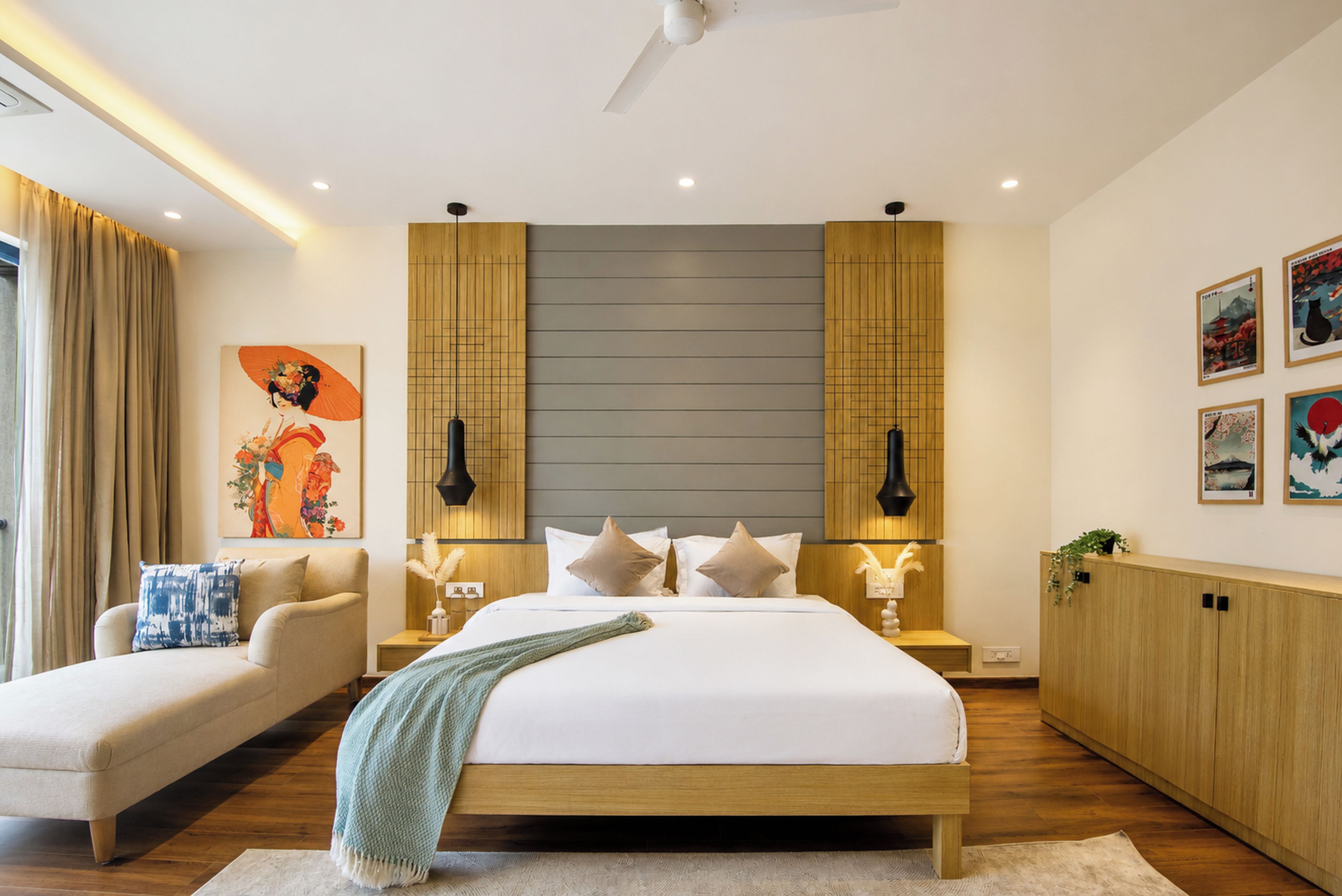 Une chambre moderne avec un grand lit, un canapé et des œuvres d’art accrochées aux murs.