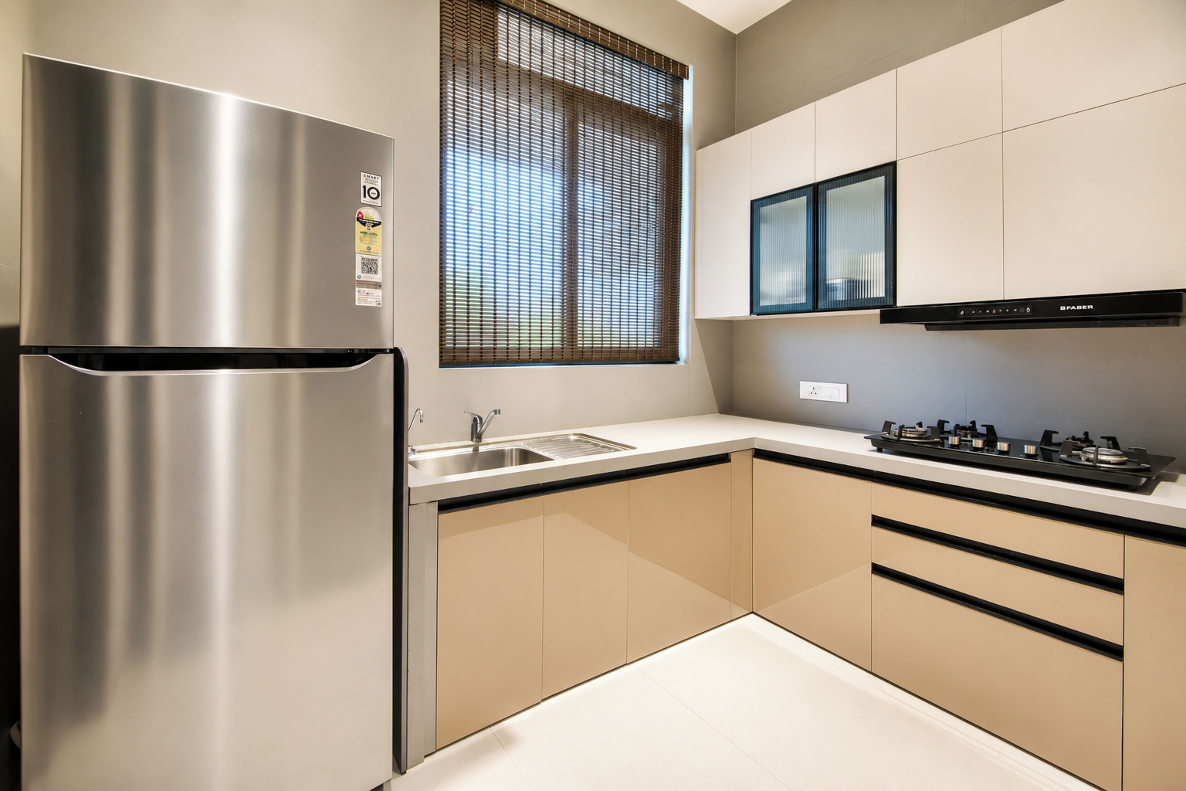 A modern kitchen with a stainless steel refrigerator, a gas stove, and a window with blinds.