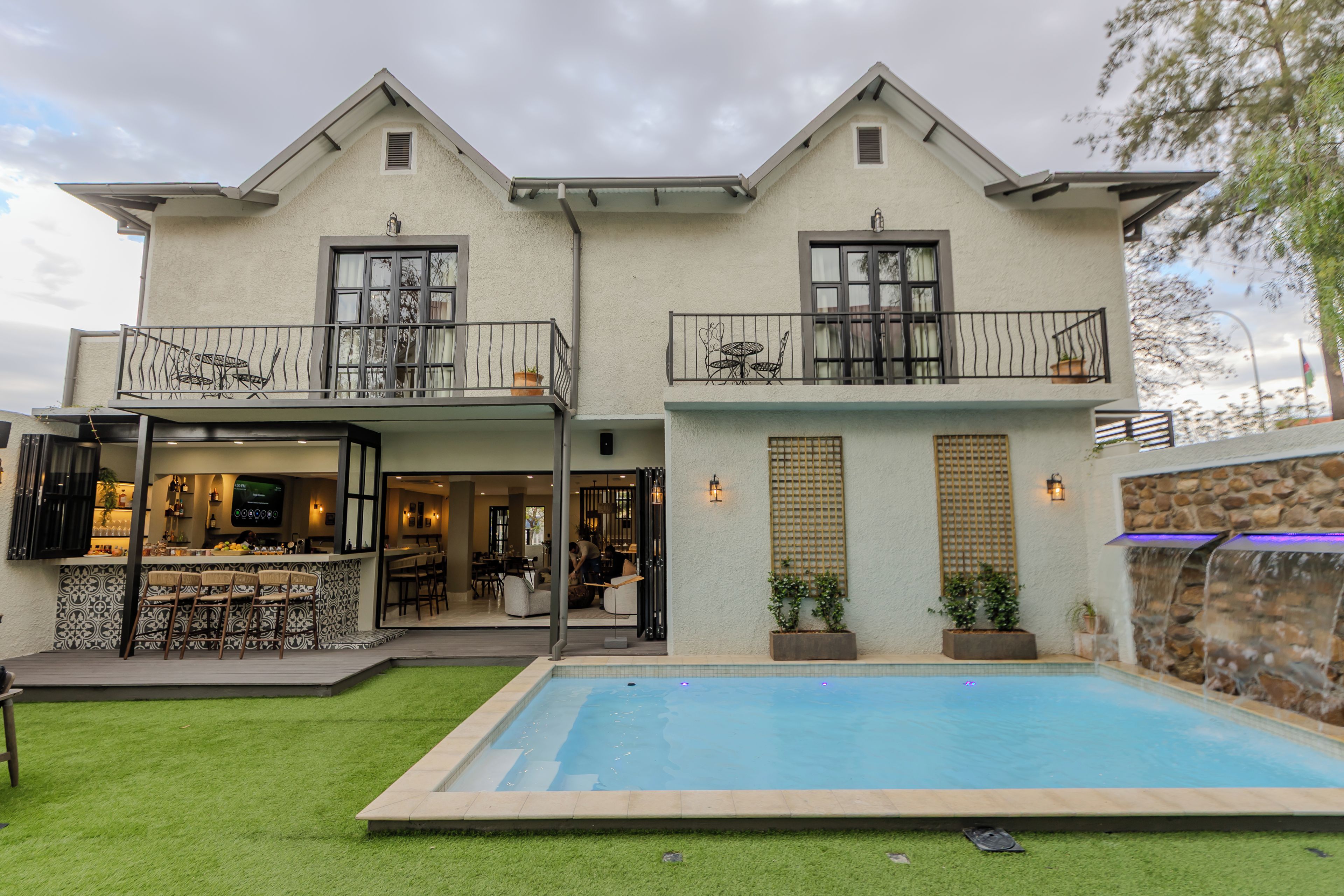 Casa de dos pisos con piscina, barra exterior y zona de comedor.