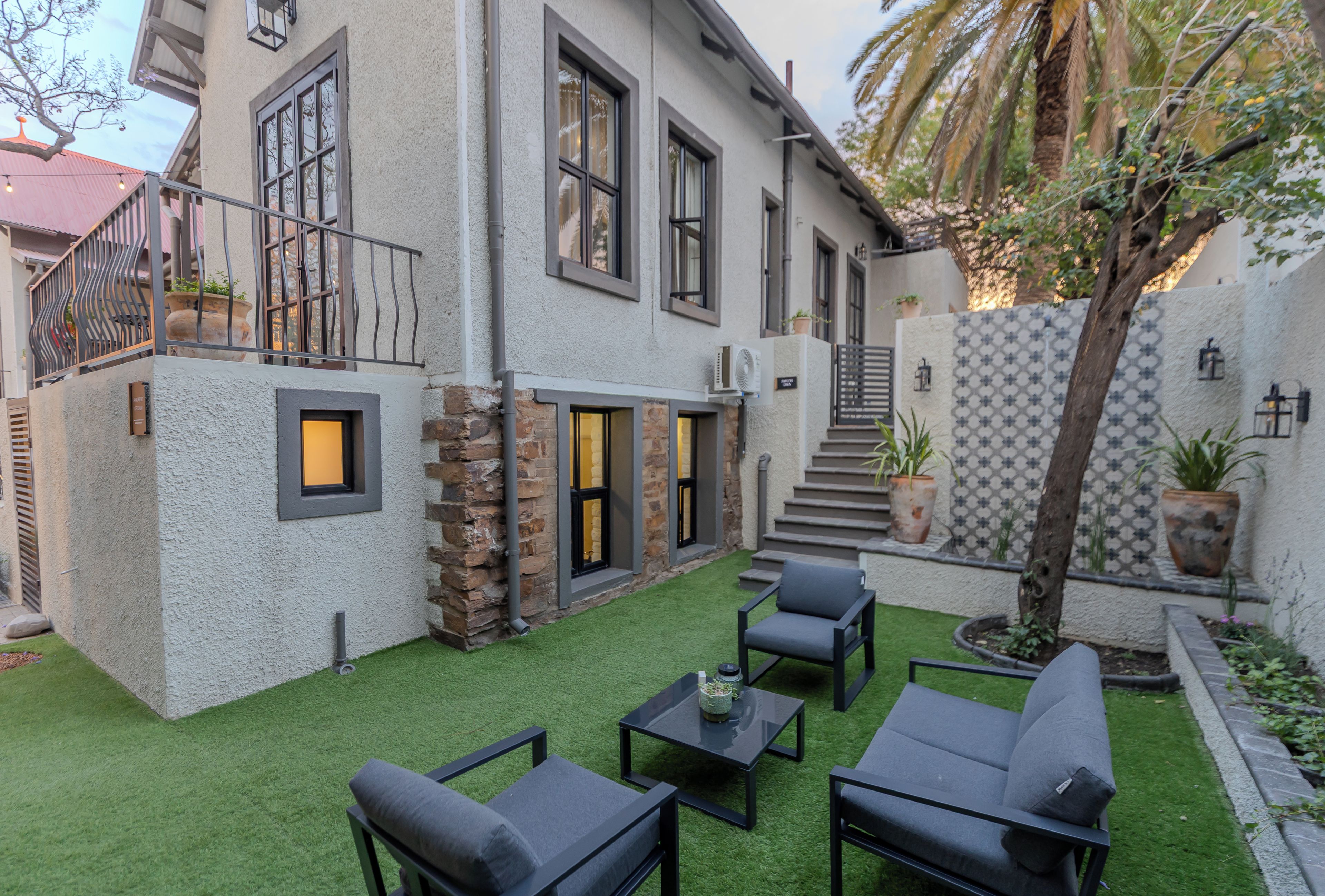 Une maison moderne dotée d’un patio, de mobilier d’extérieur et d’un escalier menant à l’entrée.