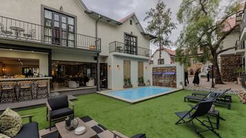 Une cour avec une piscine, un espace aménagé pour se détendre en plein air et un coin bar.