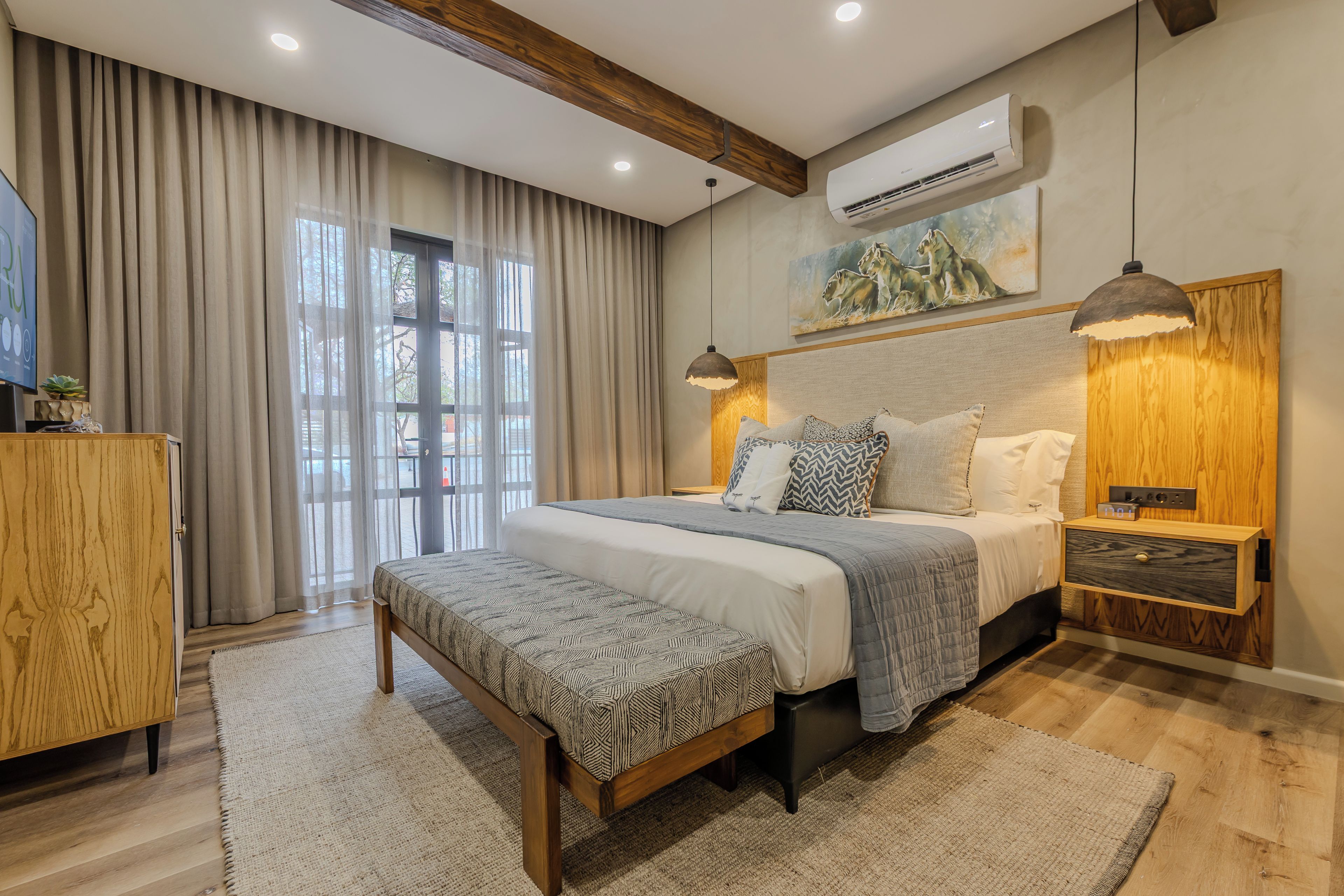 Une chambre à coucher moderne avec un grand lit, des tables de chevet, un banc et un tableau au mur.