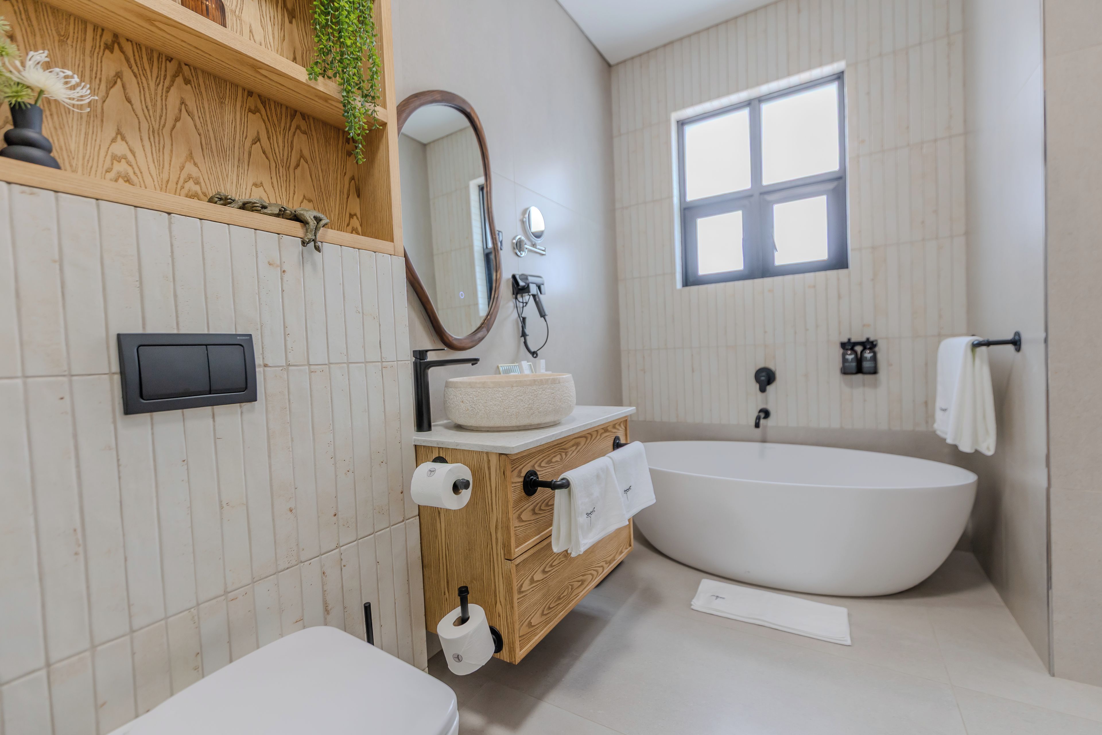Une salle de bain moderne avec une baignoire sur pieds, un meuble-lavabo en bois et un grand miroir.