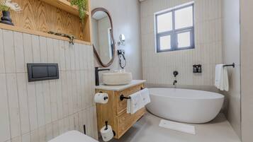 Une salle de bain moderne avec une baignoire sur pieds, un meuble-lavabo en bois et un grand miroir.