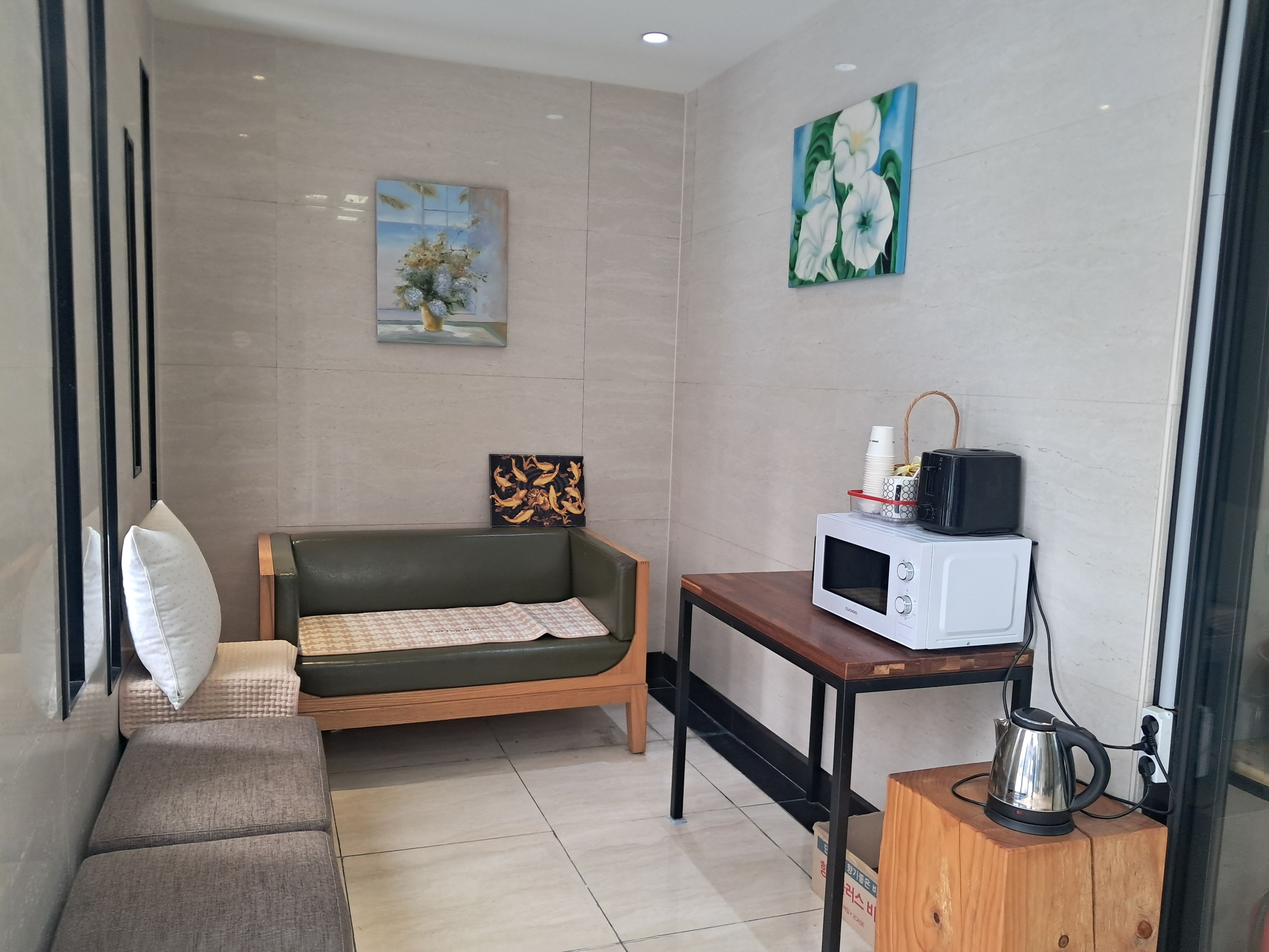A small, modern room with a sofa, a table with a microwave, and a kettle.
