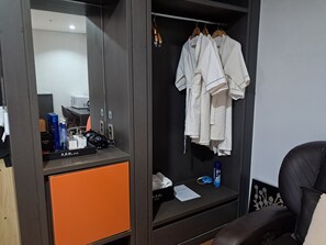 Habitación de hotel con armario que contiene un espejo, un escritorio con artículos de aseo y una silla.