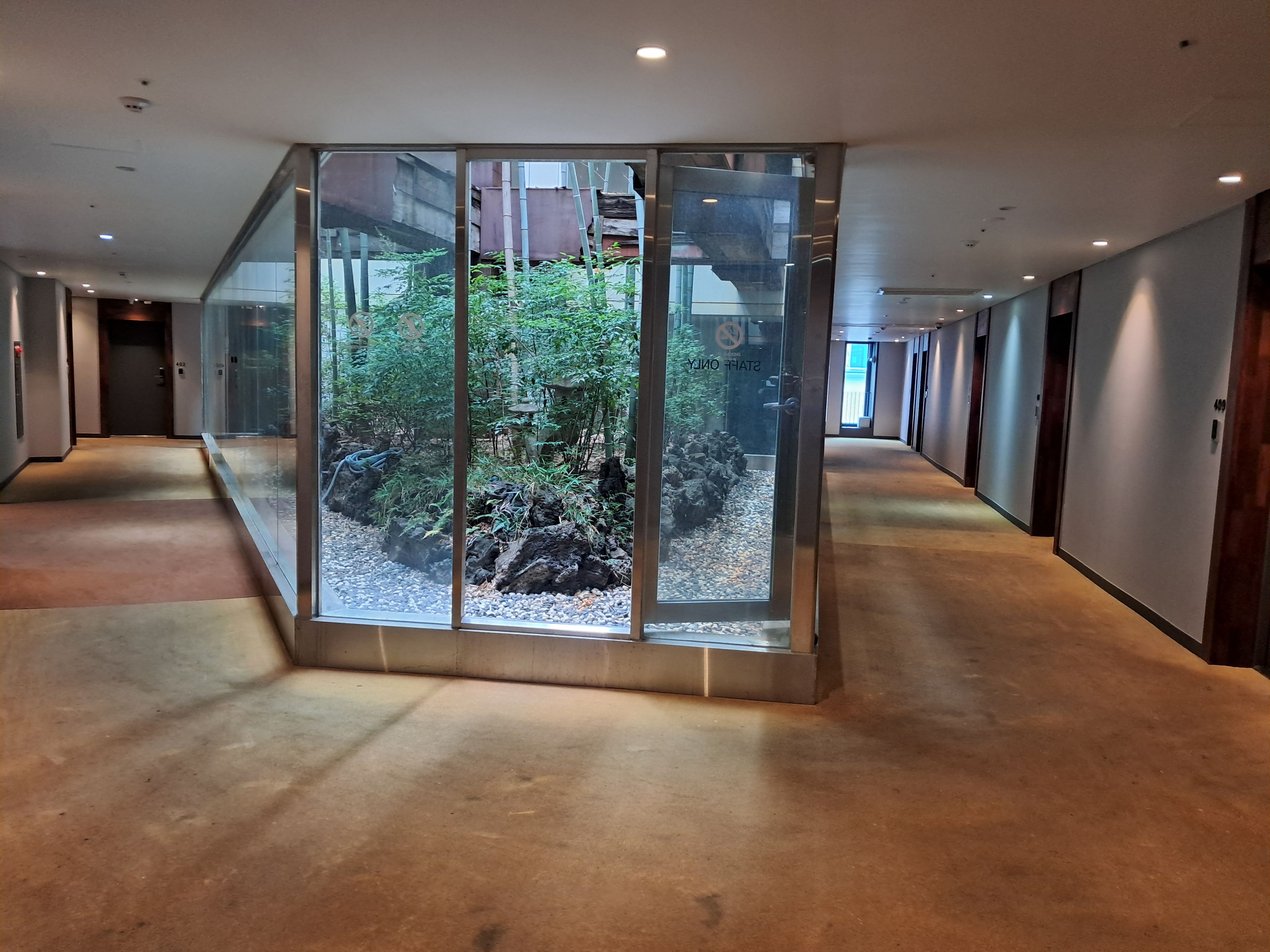 A hallway with a glass enclosure featuring a rock garden and bamboo.