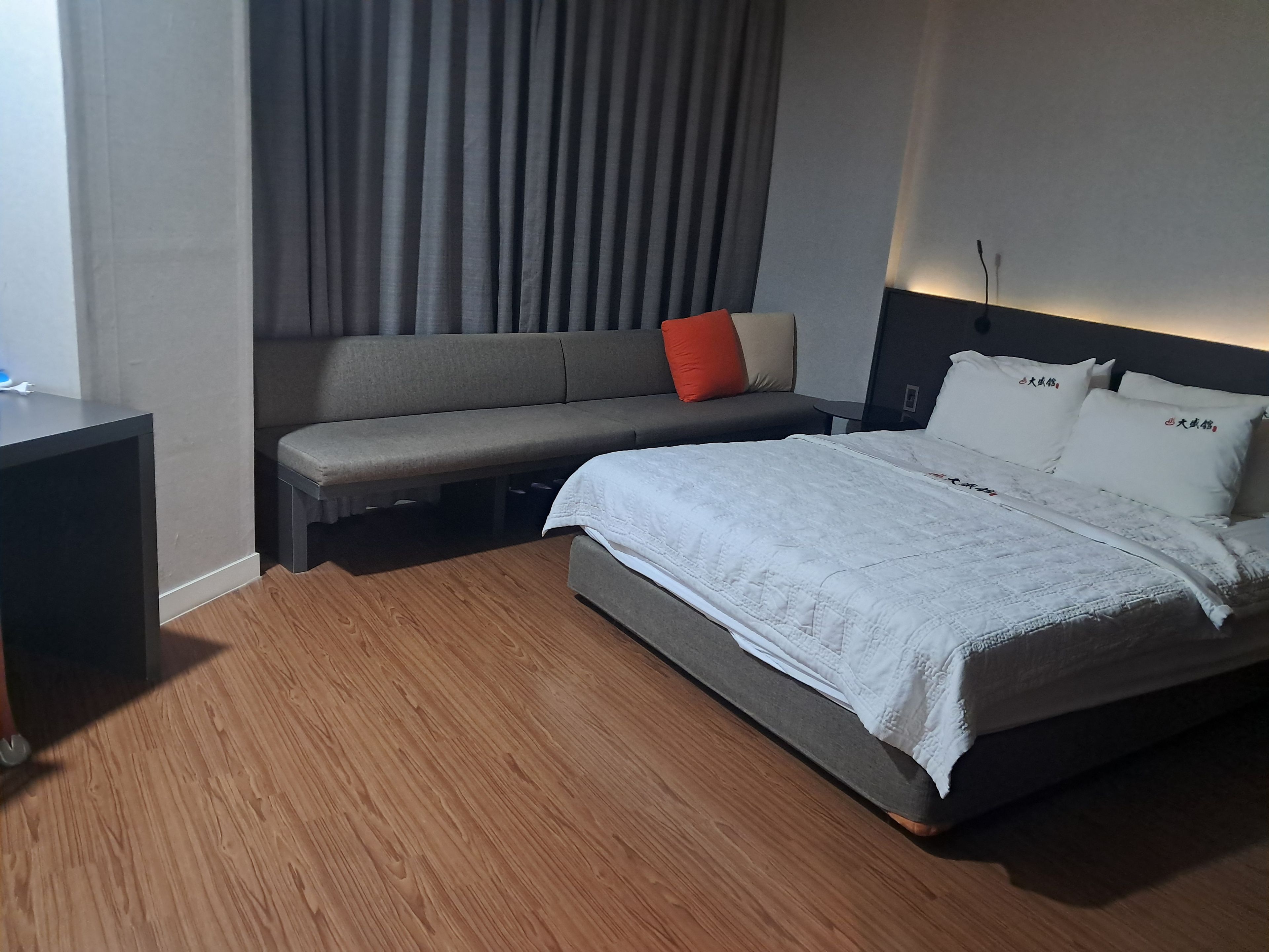 A hotel room with a bed, a bench, and a desk.