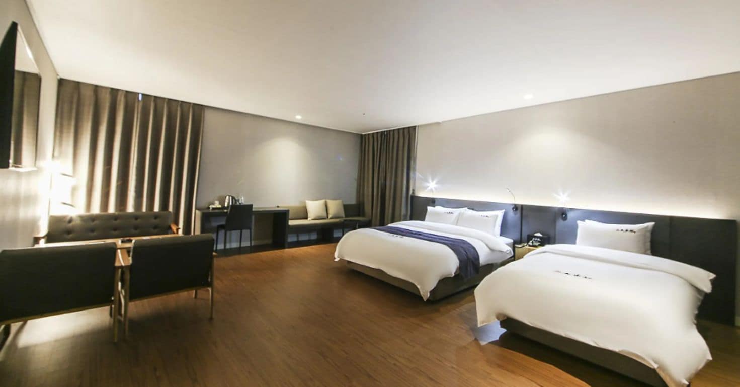 A modern hotel room with a large bed, a desk, and a seating area.