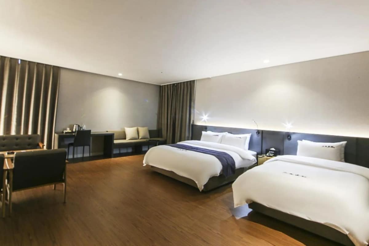 A modern hotel room with a large bed, a desk, and a seating area.