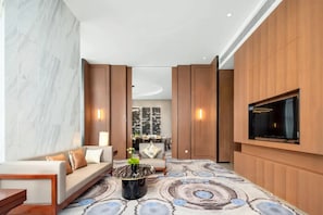 A modern living room with a sofa, coffee table, and a flat-screen TV mounted on the wall.