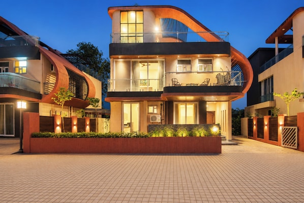 A modern multi-story building with a balcony and a well-lit entrance.