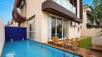 A modern building with a swimming pool, outdoor seating, and a unique architectural design.