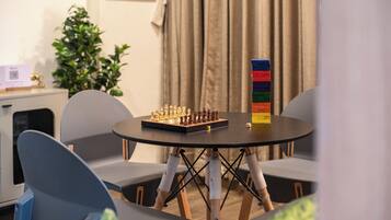 A chessboard on a round table with chairs around it.