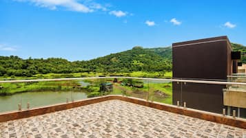 A terrace with a view of a river and hills.
