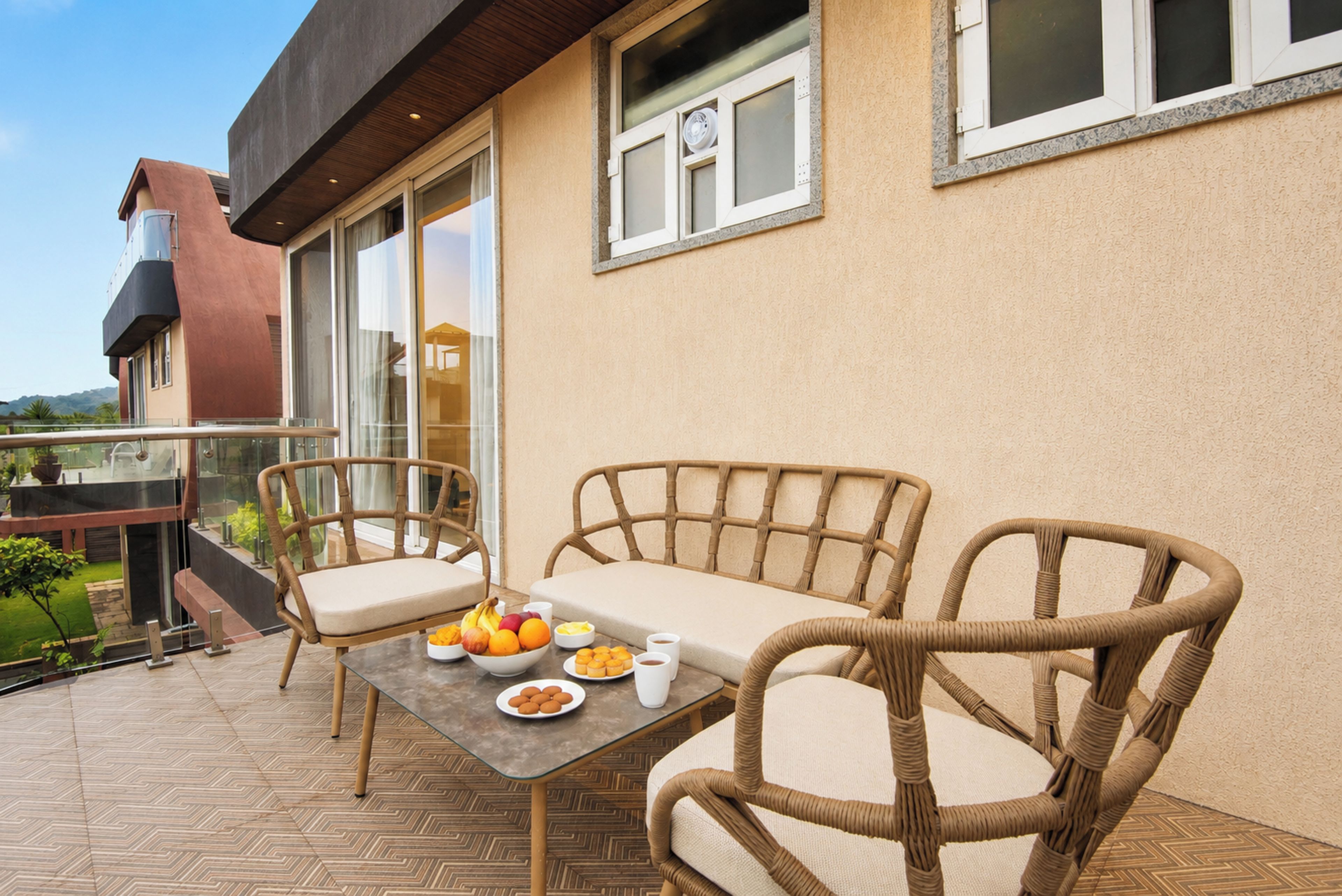 A balcony with wicker furniture and a table set with fruits and a cup.