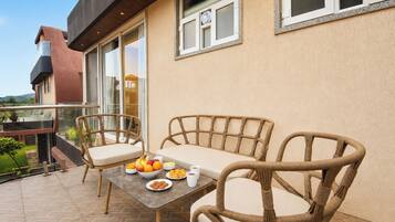 A balcony with wicker furniture and a table set with fruits and a cup.