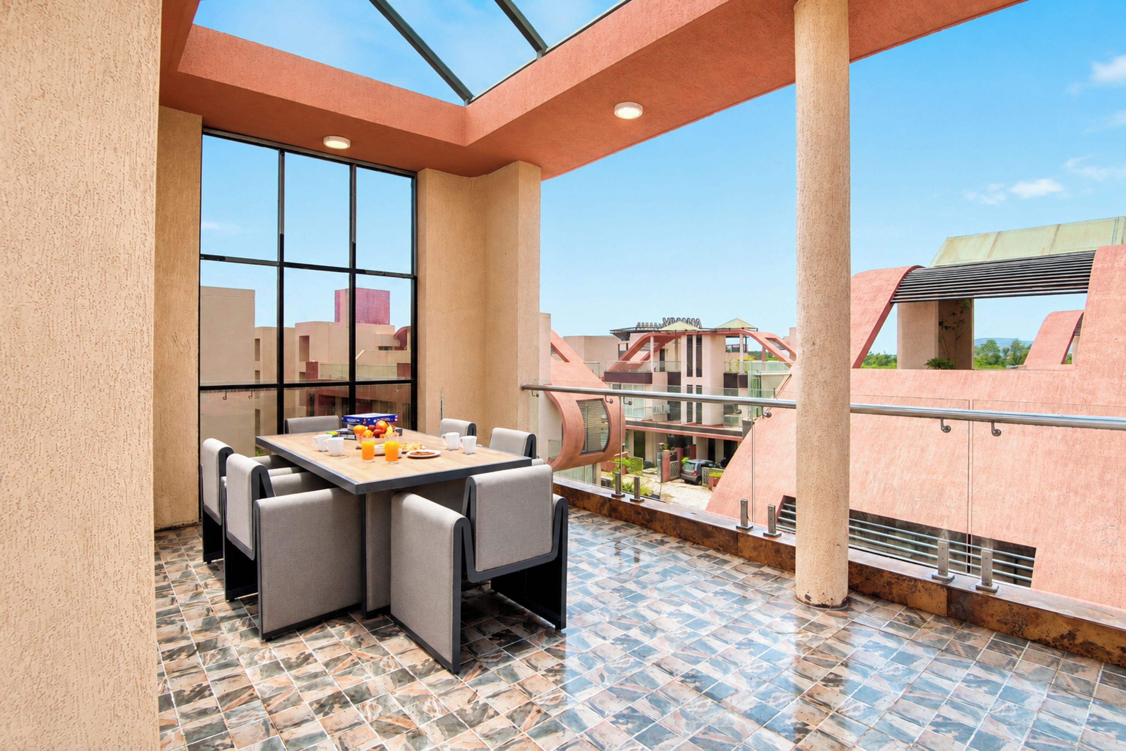 A rooftop terrace with a dining table and chairs, a view of the cityscape, and a tiled floor.