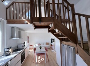 Een moderne keuken met een eethoek, een houten trap en een klein balkon.