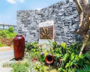 Un muro de piedra con una placa que dice 'VILLA UBUD' y un jarrón grande.