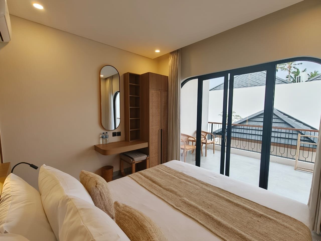 Una camera d'albergo con un letto, una scrivania, uno specchio e vista sull'esterno.
