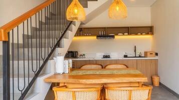 Una cocina moderna con una mesa de comedor de madera, sillas de mimbre e iluminación colgante.