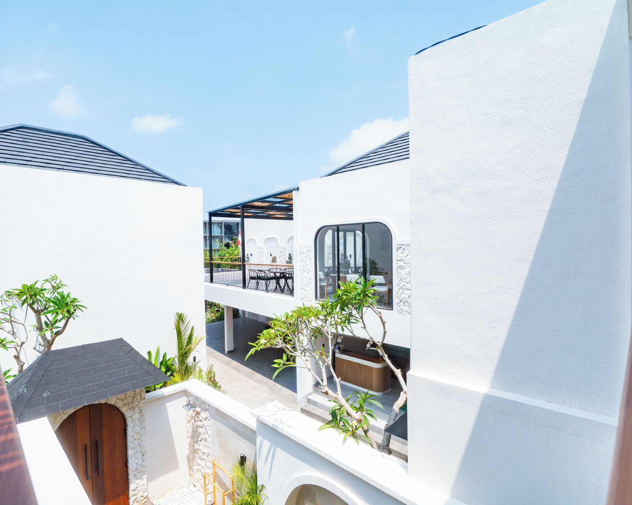 Un edificio moderno con patio, mesas al aire libre y un muro de piedra.