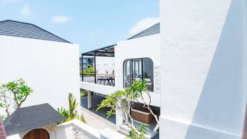 Un edificio moderno con patio, mesas al aire libre y un muro de piedra.