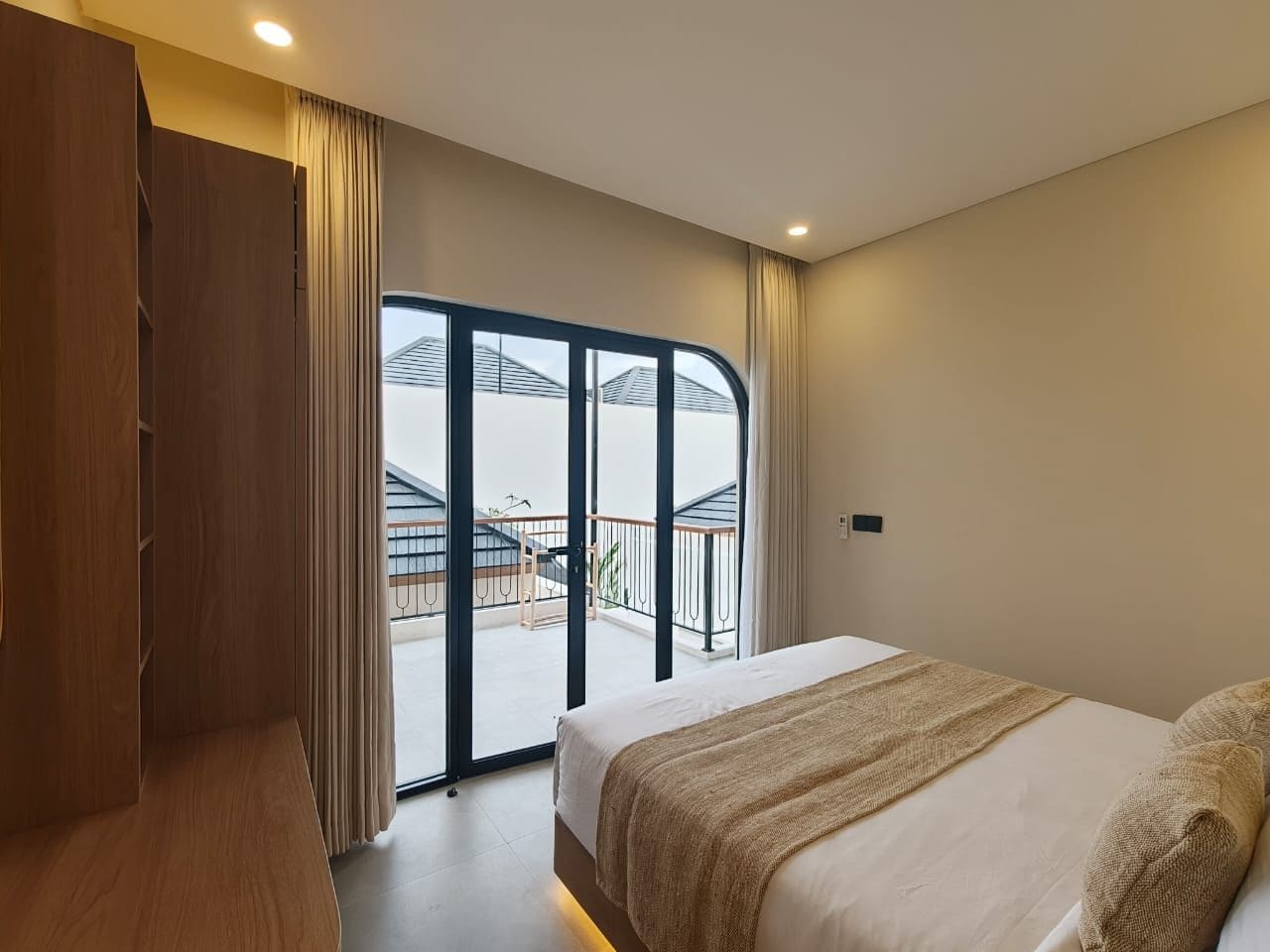 Una camera d'albergo con un letto, un armadio, un balcone con vista e una porta scorrevole in vetro.