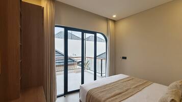 Una camera d'albergo con un letto, un armadio, un balcone con vista e una porta scorrevole in vetro.