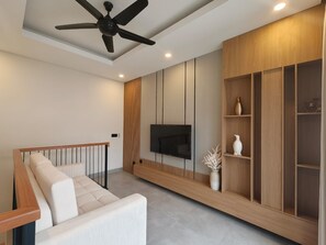 Un soggiorno moderno con un divano, una televisione a parete e un mobiletto in legno con ripiani.