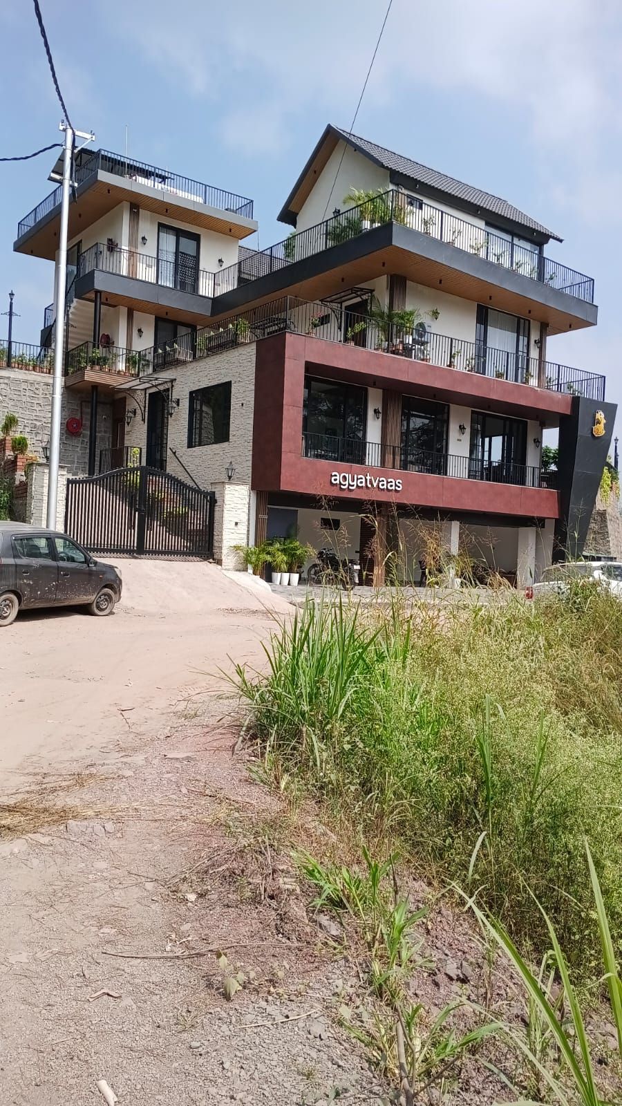 Un immeuble à plusieurs étages doté d’une architecture moderne, avec des balcons agrémentés de rampes et de plantes en pot.
