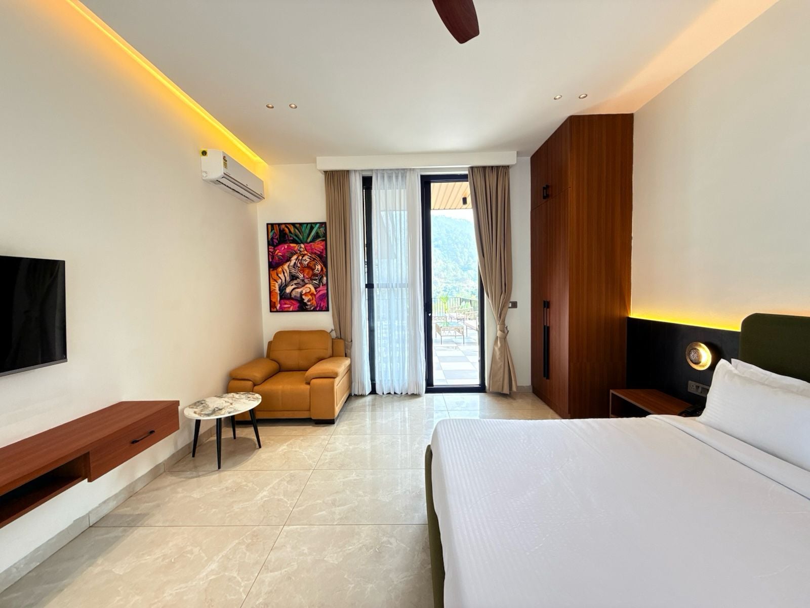 Ein Hotelzimmer mit einem Bett, einem Sofa, einem kleinen Tisch, einem Fernseher und einem Gemälde.