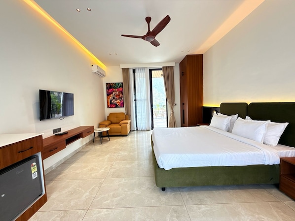 A hotel room with a bed, a desk, a chair, a TV, and a ceiling fan.
