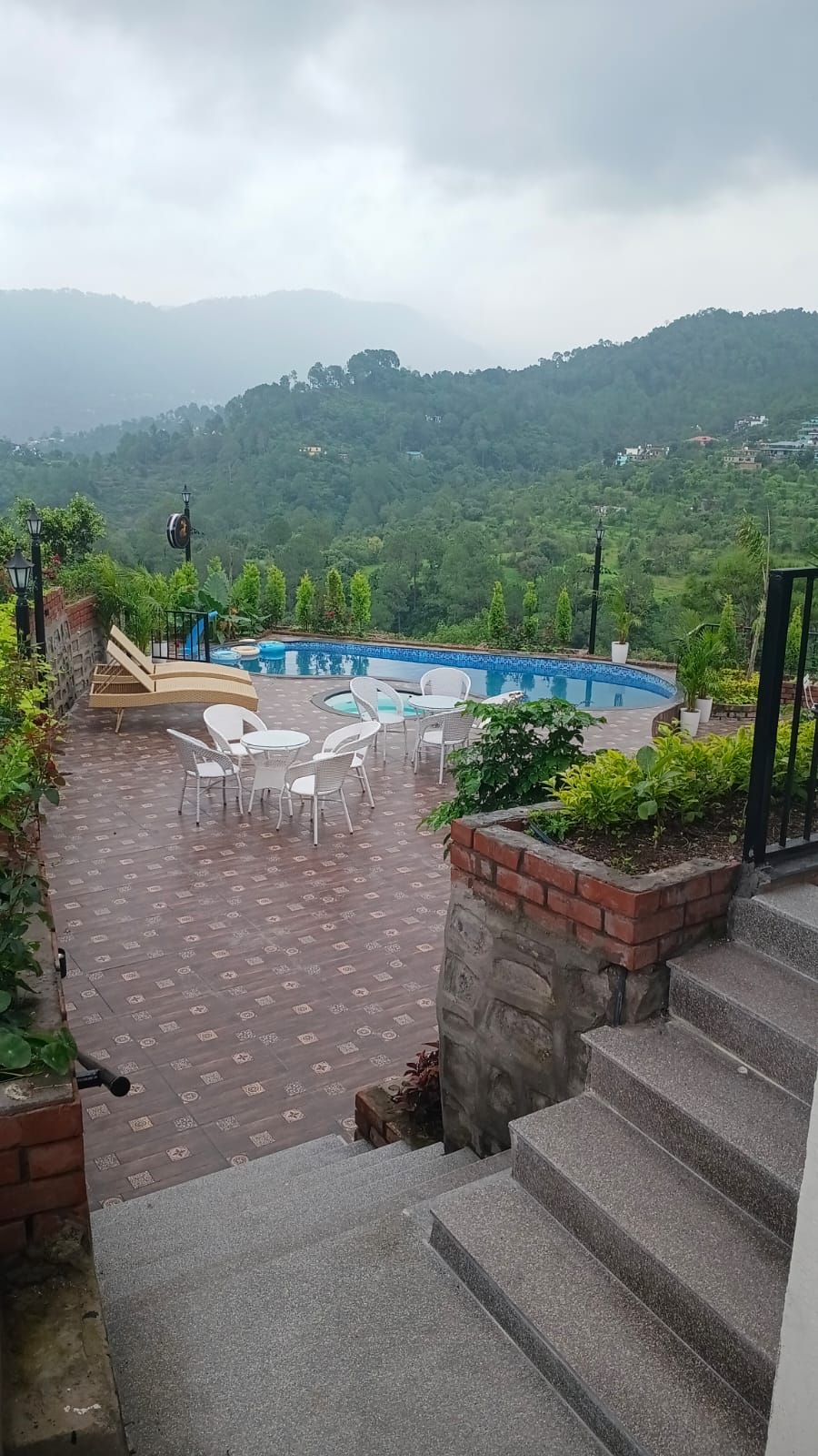 Zona de piscina con escalones descendentes, rodeada de vegetación y con vistas a un paisaje montañoso.