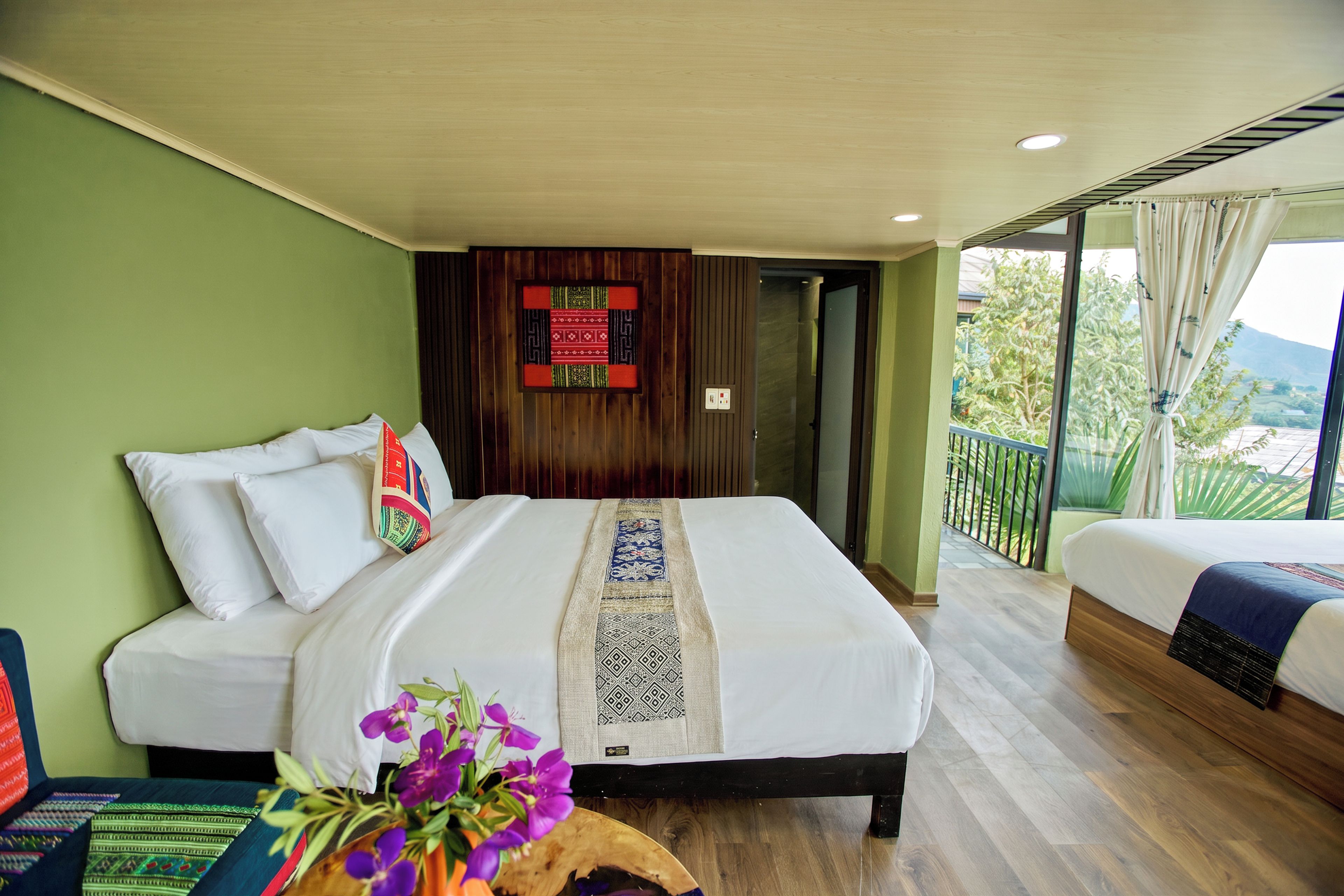 A hotel room with a large bed, a smaller bed, and a balcony with a view.