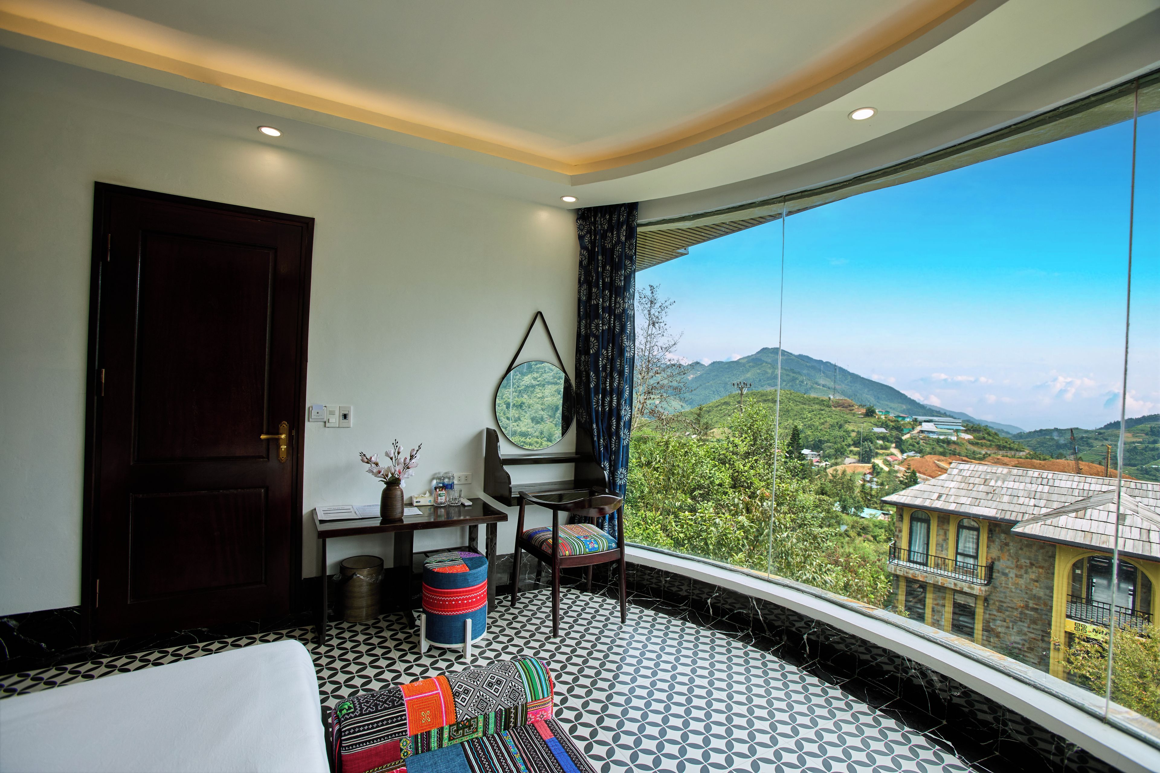 A room with a large window, a bed, a desk, and a chair.